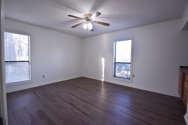 spare room with dark wood-style floors, a textured ceiling, and a ceiling fan