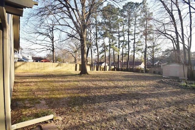 view of yard with a storage shed, fence, and an outbuilding