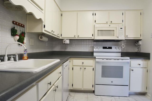 kitchen with white appliances, a sink, marble finish floor, decorative backsplash, and dark countertops