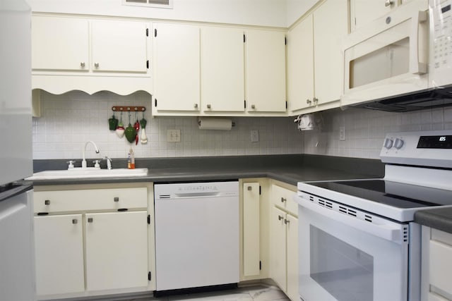 kitchen featuring white appliances, dark countertops, a sink, and tasteful backsplash