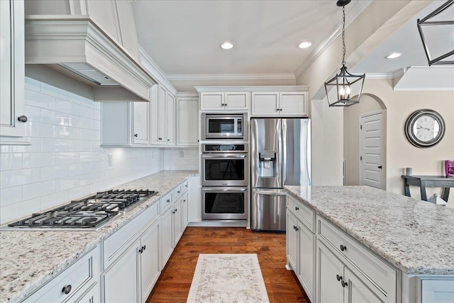 kitchen featuring white cabinets, appliances with stainless steel finishes, dark wood-style floors, crown molding, and custom range hood