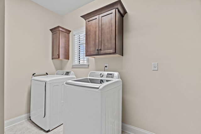 laundry area with independent washer and dryer, light tile patterned flooring, baseboards, and cabinet space