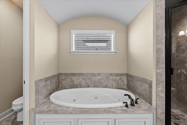 bathroom featuring toilet, a jetted tub, and vaulted ceiling
