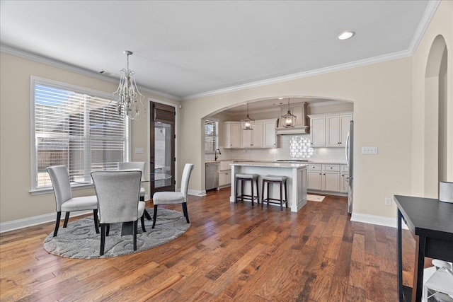dining room featuring baseboards, arched walkways, and dark wood finished floors