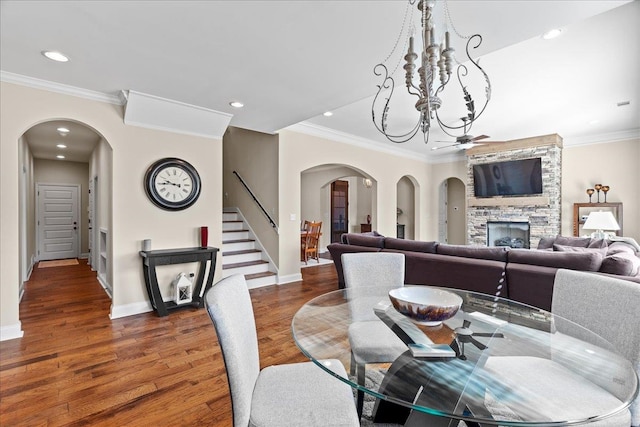 dining space featuring arched walkways, wood finished floors, ceiling fan, and stairs