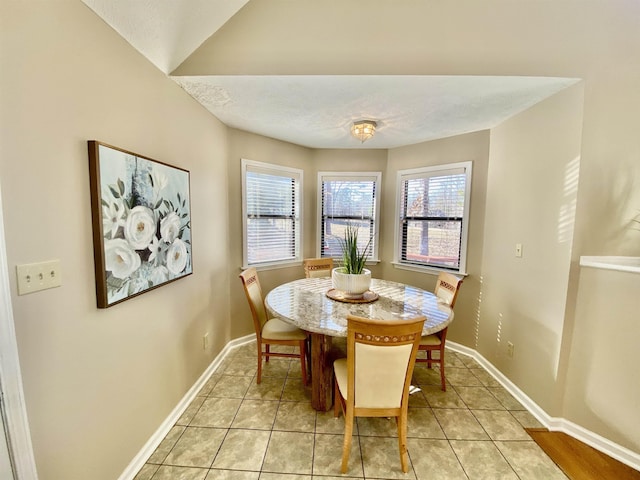 dining area featuring a textured ceiling, baseboards, and light tile patterned floors