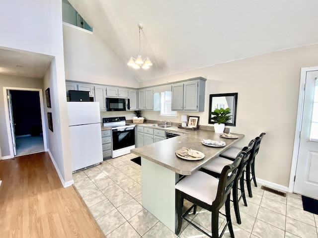 kitchen with electric stove, visible vents, freestanding refrigerator, black microwave, and a peninsula