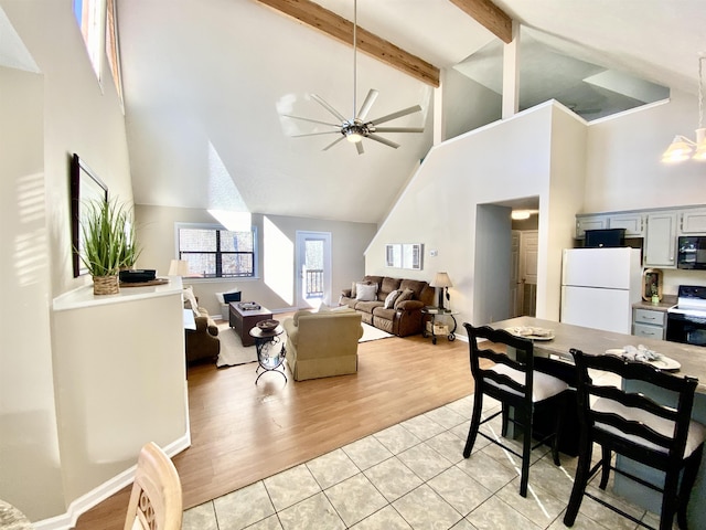 dining space featuring ceiling fan, high vaulted ceiling, beamed ceiling, and light wood-style flooring