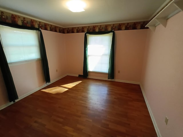 spare room featuring baseboards and wood finished floors