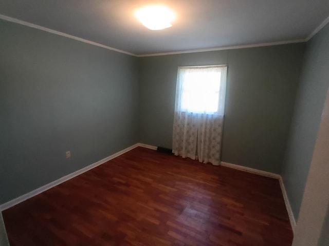 empty room featuring ornamental molding, dark wood-type flooring, and baseboards