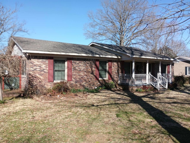 ranch-style house with a porch, a front yard, brick siding, and a shingled roof