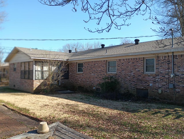 exterior space featuring crawl space, a shingled roof, a lawn, and brick siding