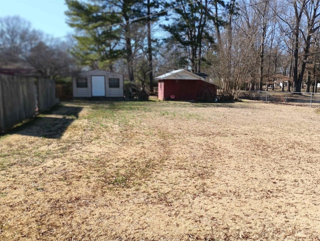 view of yard featuring fence, an outdoor structure, and a storage unit