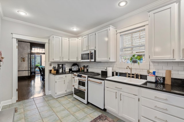 kitchen with white appliances, crown molding, backsplash, and a sink