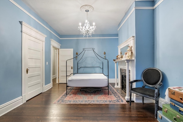 bedroom with baseboards, a fireplace, wood finished floors, and an inviting chandelier