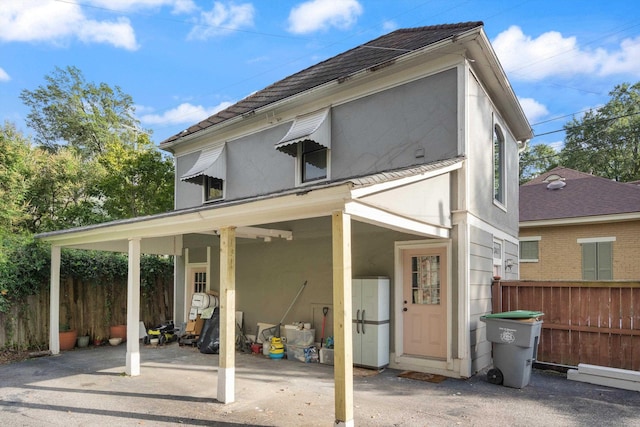 back of property featuring fence, a carport, and stucco siding