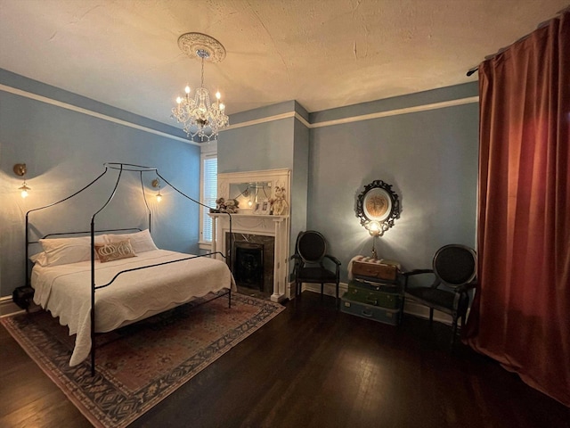 bedroom with a chandelier, a fireplace, baseboards, and wood finished floors