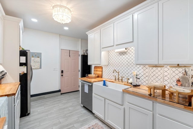 kitchen featuring decorative backsplash, appliances with stainless steel finishes, white cabinetry, a sink, and wood counters