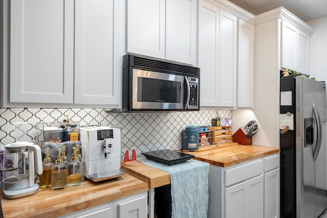 kitchen with white cabinetry, butcher block countertops, appliances with stainless steel finishes, and decorative backsplash