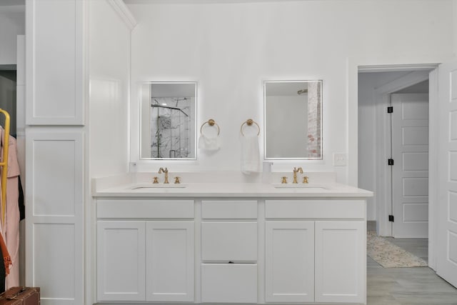 bathroom featuring double vanity, a shower, a sink, and wood finished floors