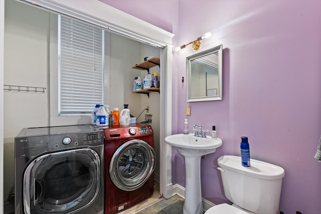 half bathroom featuring washing machine and dryer, a sink, and toilet