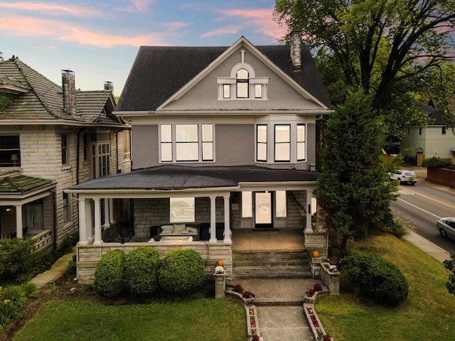 view of front facade with covered porch, a chimney, and stucco siding