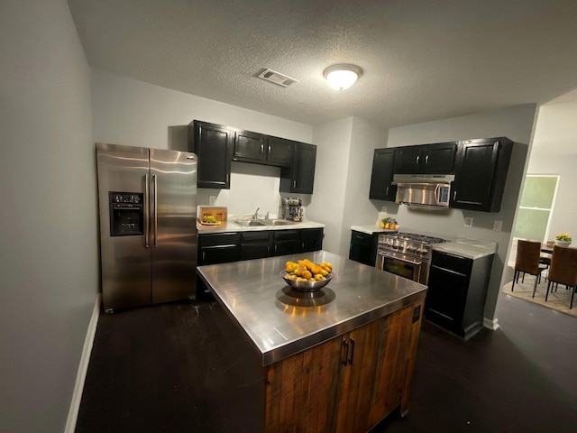 kitchen with dark cabinets, a sink, visible vents, appliances with stainless steel finishes, and stainless steel counters