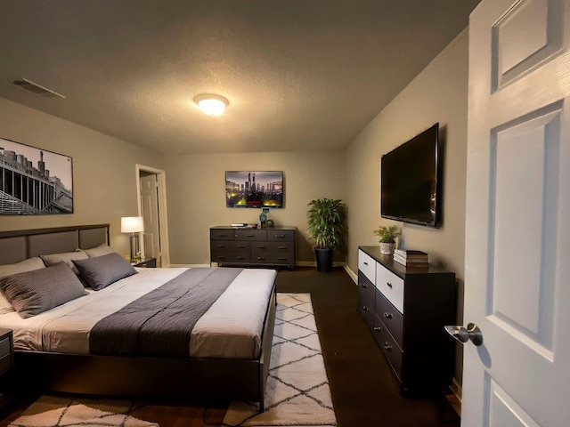 bedroom featuring baseboards, visible vents, and a textured ceiling