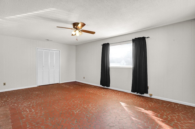 unfurnished room with a ceiling fan, visible vents, a textured ceiling, and baseboards