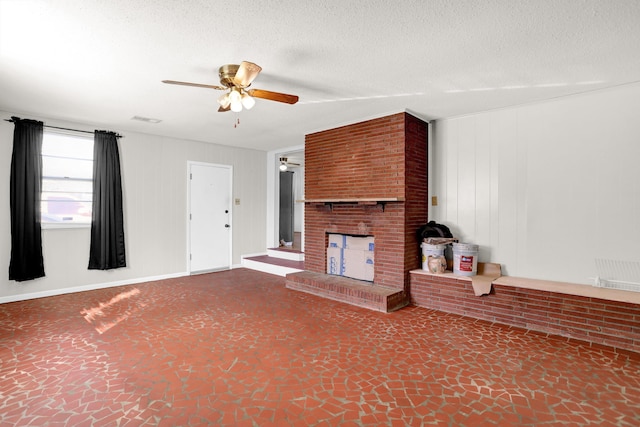 unfurnished living room featuring a textured ceiling, a fireplace, visible vents, and a ceiling fan