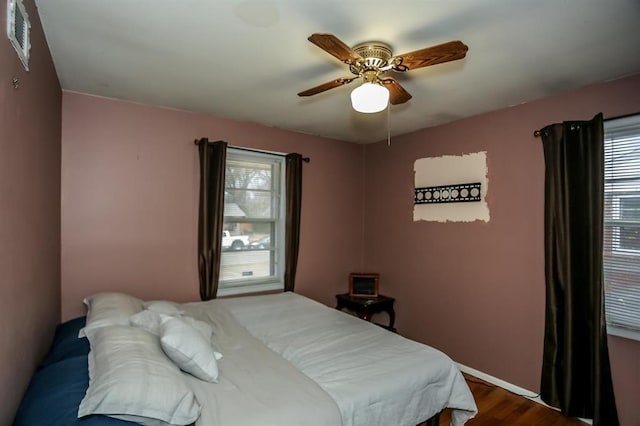 bedroom featuring dark wood finished floors, visible vents, and ceiling fan