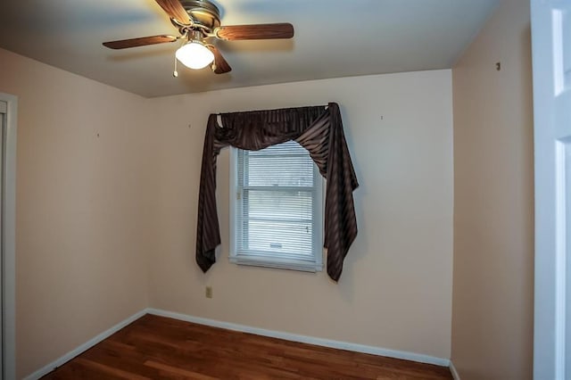 empty room with wood finished floors, a ceiling fan, and baseboards