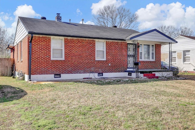 view of front of home featuring a front yard, a chimney, fence, and brick siding