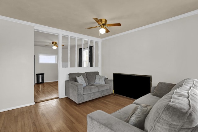 living area featuring ceiling fan, ornamental molding, wood finished floors, and baseboards