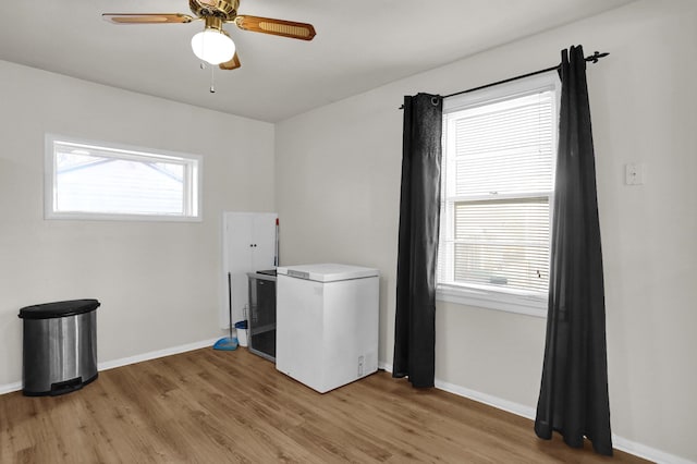 clothes washing area with light wood-style floors, ceiling fan, and baseboards