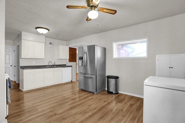 kitchen featuring white appliances, a sink, white cabinetry, light wood-style floors, and dark countertops