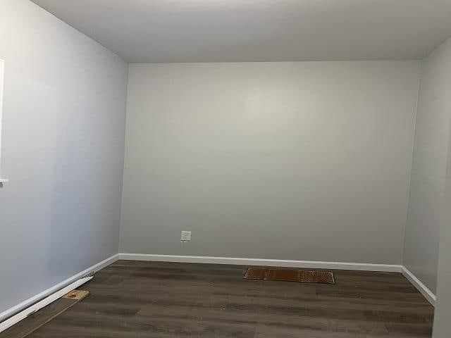 spare room featuring dark wood-style floors and baseboards