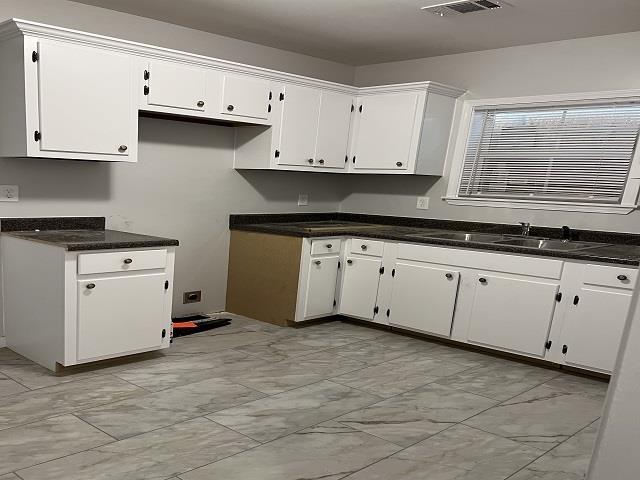 kitchen featuring marble finish floor, a sink, and white cabinets