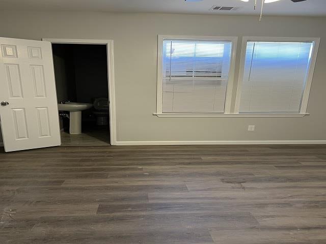 spare room featuring ceiling fan, wood finished floors, visible vents, and baseboards