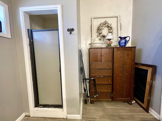 bathroom with wood tiled floor, a shower stall, and baseboards