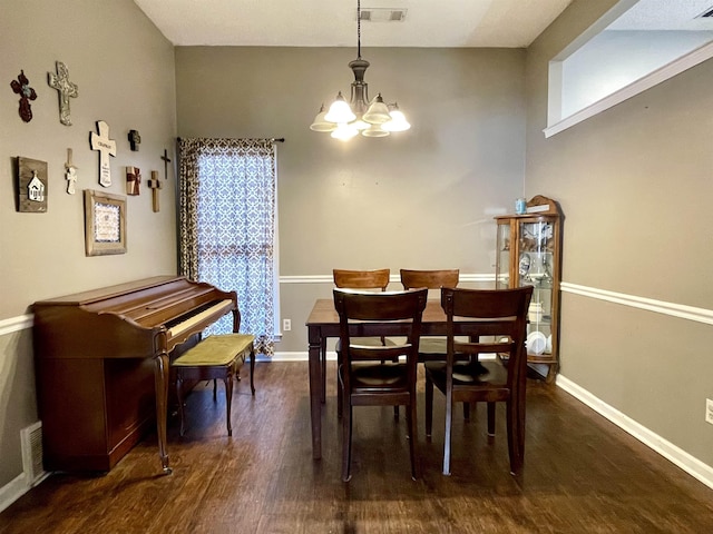 dining space featuring baseboards, wood finished floors, visible vents, and an inviting chandelier