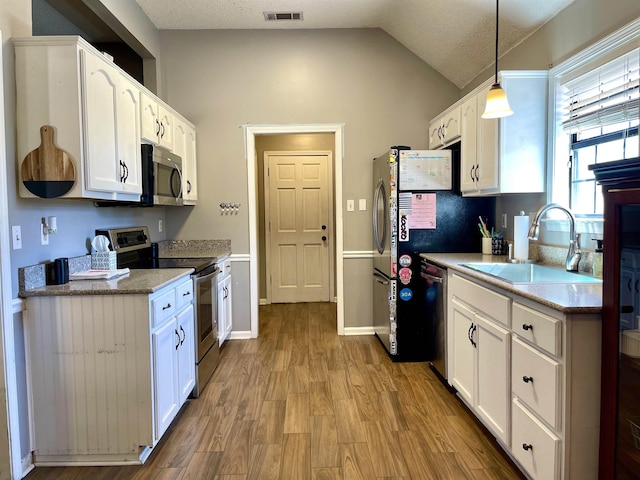 kitchen featuring appliances with stainless steel finishes, a sink, visible vents, and white cabinetry