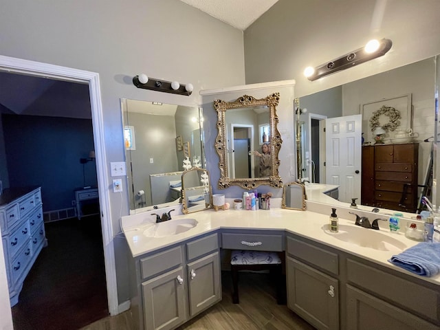 full bath with lofted ceiling, wood finished floors, a sink, and visible vents