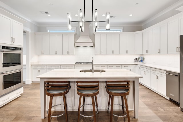 kitchen with a breakfast bar, white cabinetry, stainless steel appliances, and a sink