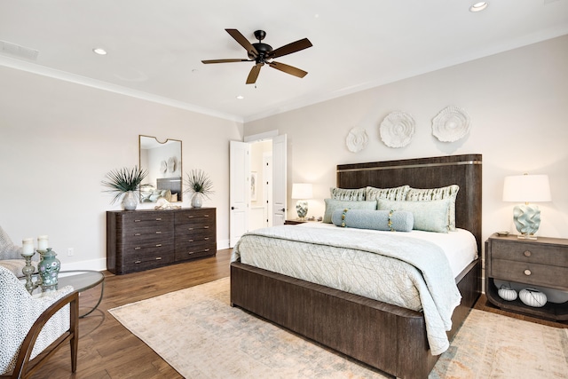 bedroom featuring recessed lighting, wood finished floors, visible vents, baseboards, and crown molding