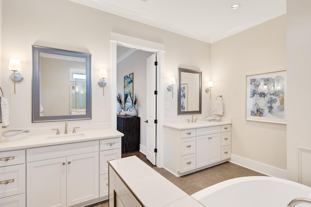 bathroom featuring a sink, two vanities, baseboards, ornamental molding, and a tub