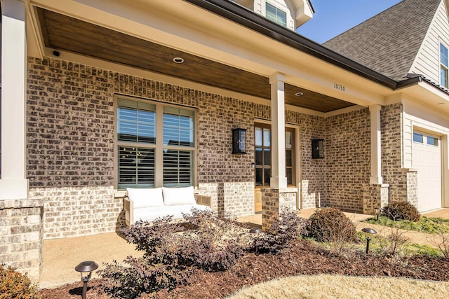 entrance to property with a garage, brick siding, and a shingled roof