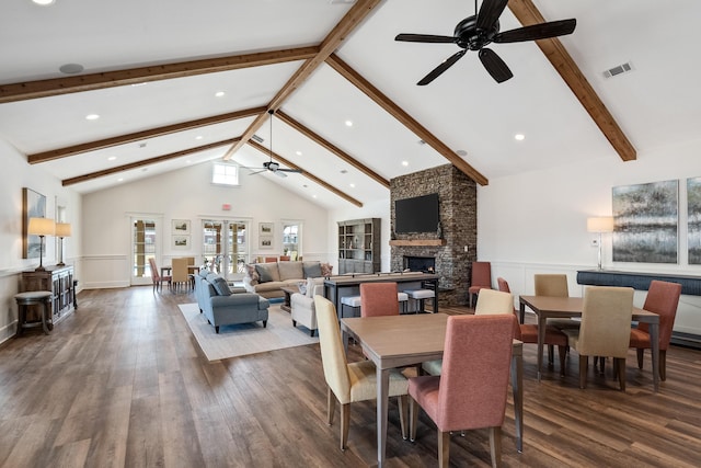 dining area featuring beam ceiling, a fireplace, visible vents, dark wood-type flooring, and high vaulted ceiling