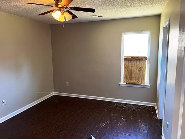 spare room featuring visible vents, a ceiling fan, a textured ceiling, baseboards, and hardwood / wood-style flooring