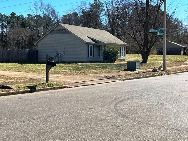 view of property exterior with a lawn and fence